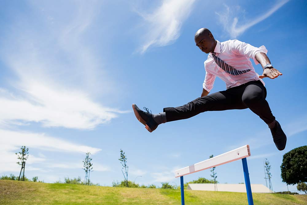 businessman jumping over hurdle