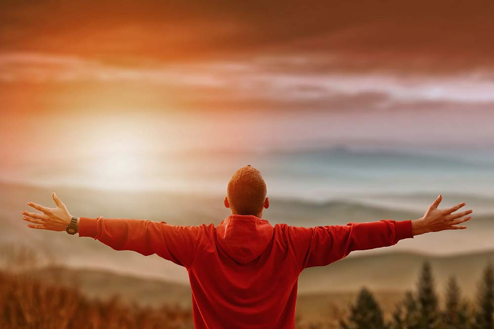 Man with arms outstretched look out at horizon