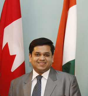 Headshot of Varun Anthony standing in front of the Canadian and Indian flags