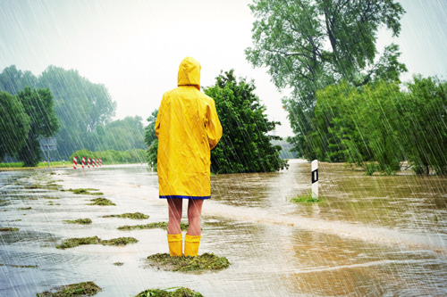 Person in rain coat standing in a flooded street