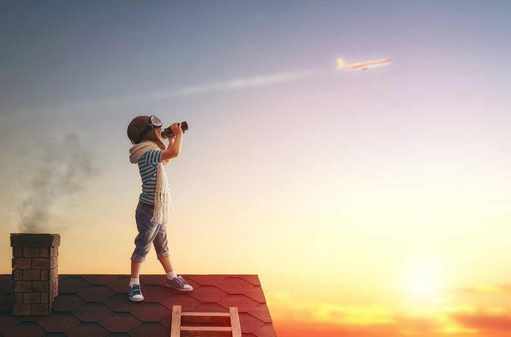 Kid on roof looking at the sky through binoculars