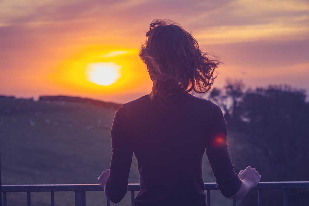 woman watching the sunrise off a balcony