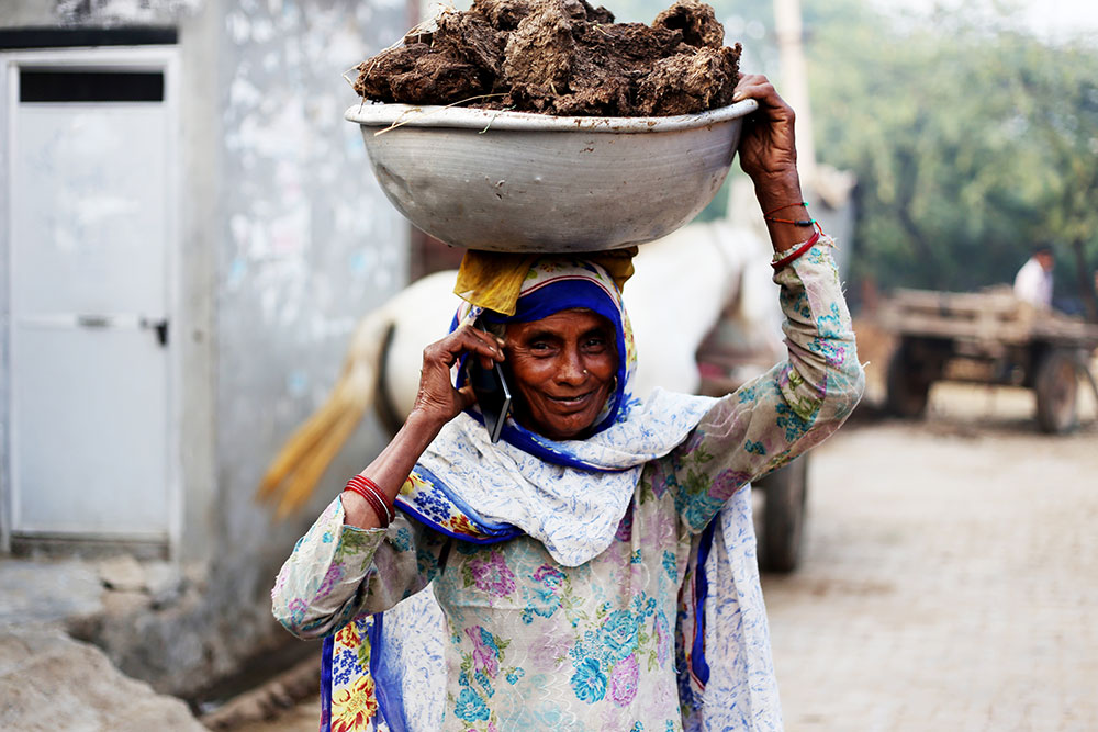 Woman carrying basket on her head and talking on a cell phone