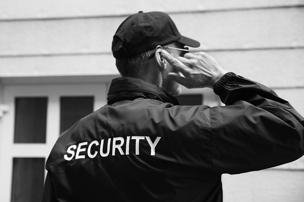 Security guard listening to earpiece outside of building