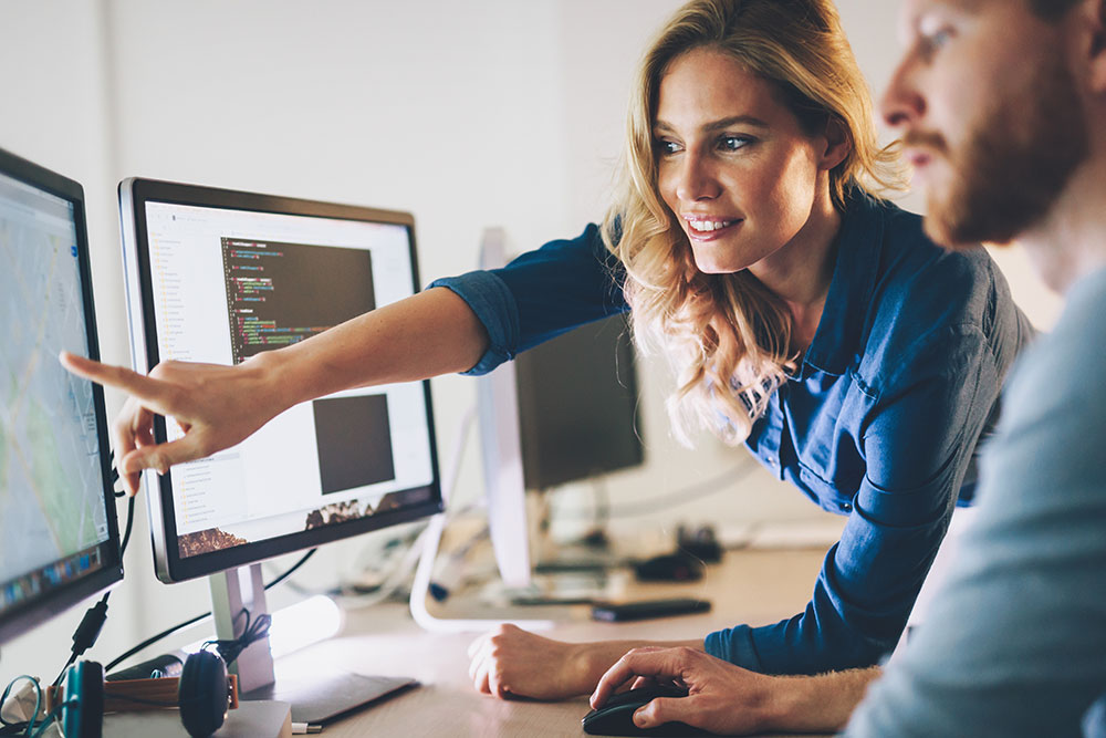 female professional pointing something out on a computer screen to her colleague