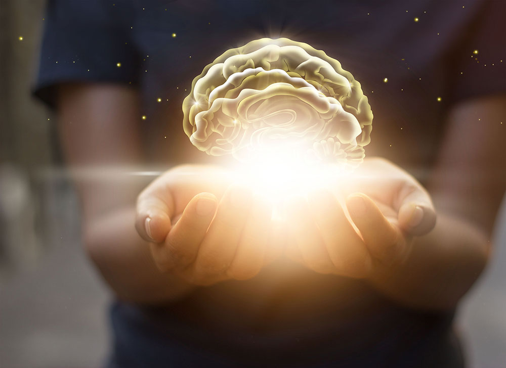 illuminated brain in palms of hands