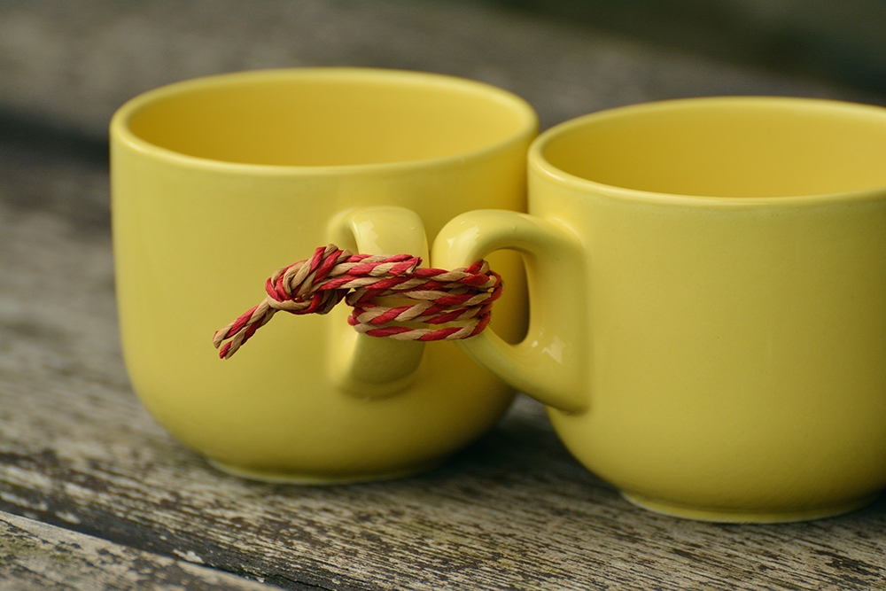 yellow coffee cups tied together with red string