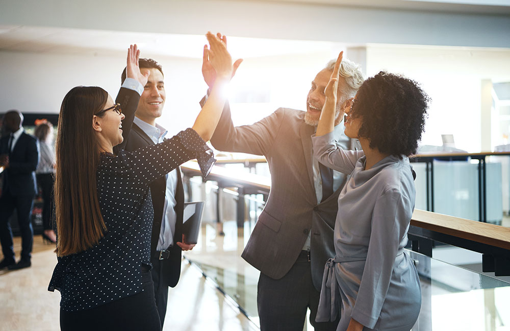 4 happy business people giving each other high fives