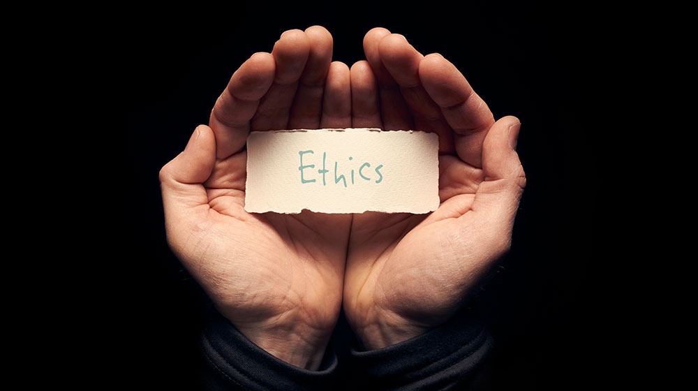 Hands holding a paper marked "ethics"