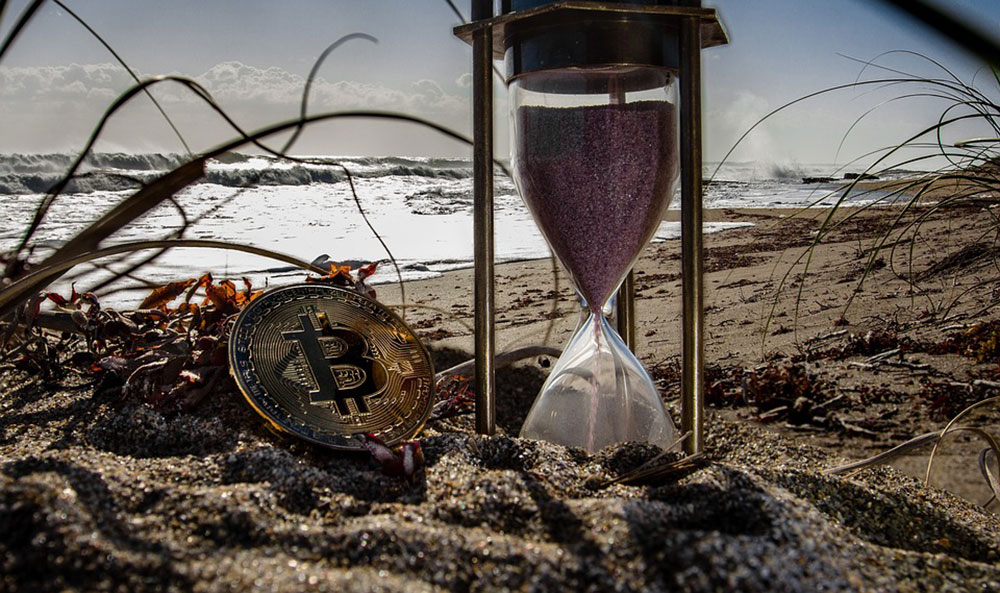 Bitcoin and hourglass on a beach