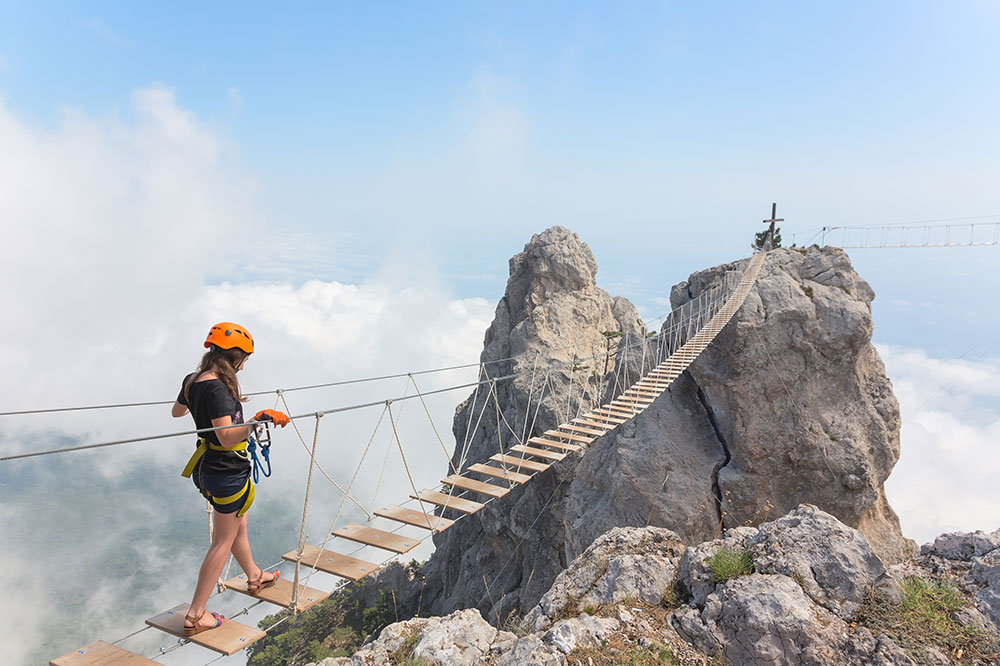 woman carefully walking over suspension bridge