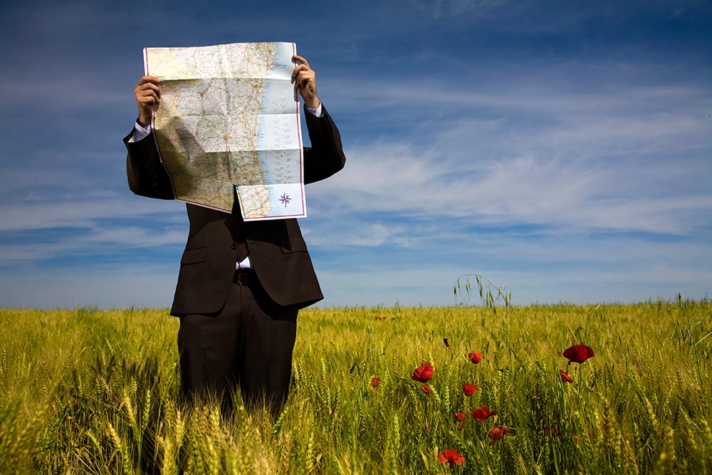 business man in field looking at map