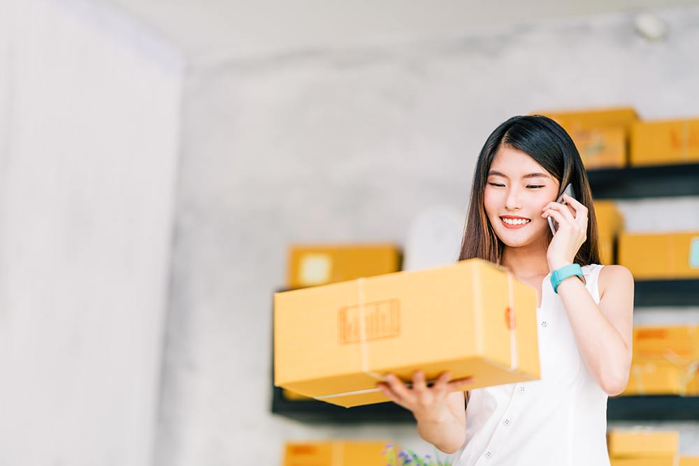 Young business owner on the phone holding a package