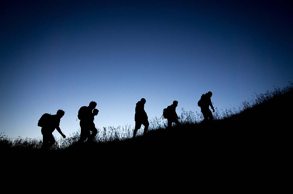 People hiking up a hill at twilight