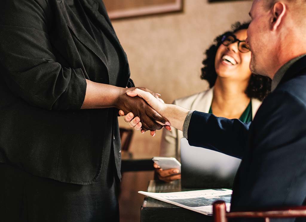 woman shaking hands with a seated person - women in business