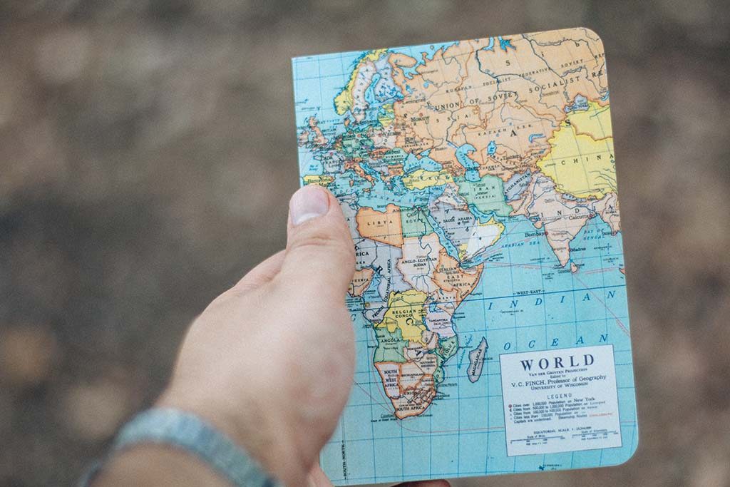 Man holds a notebook with image of world map