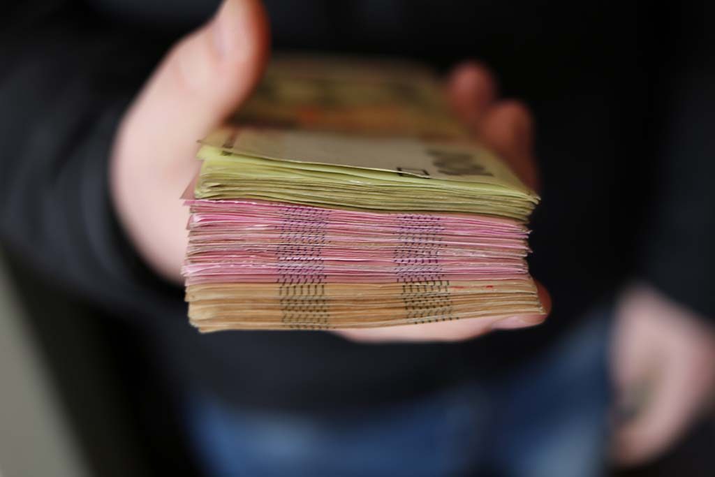 A hand holding a stack of bank notes