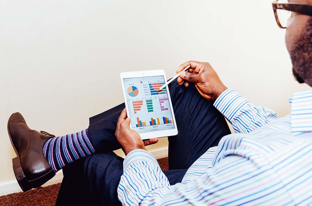 Man sitting in a chair reading a business report on a tablet