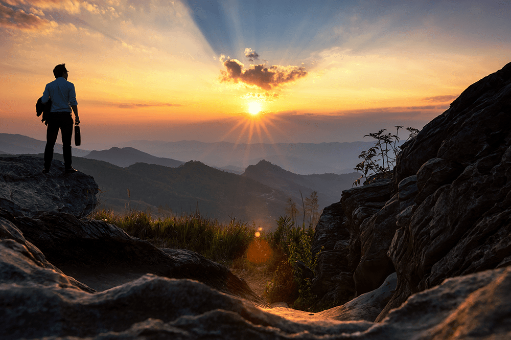 Businessman standing in mountains looking at sunrise