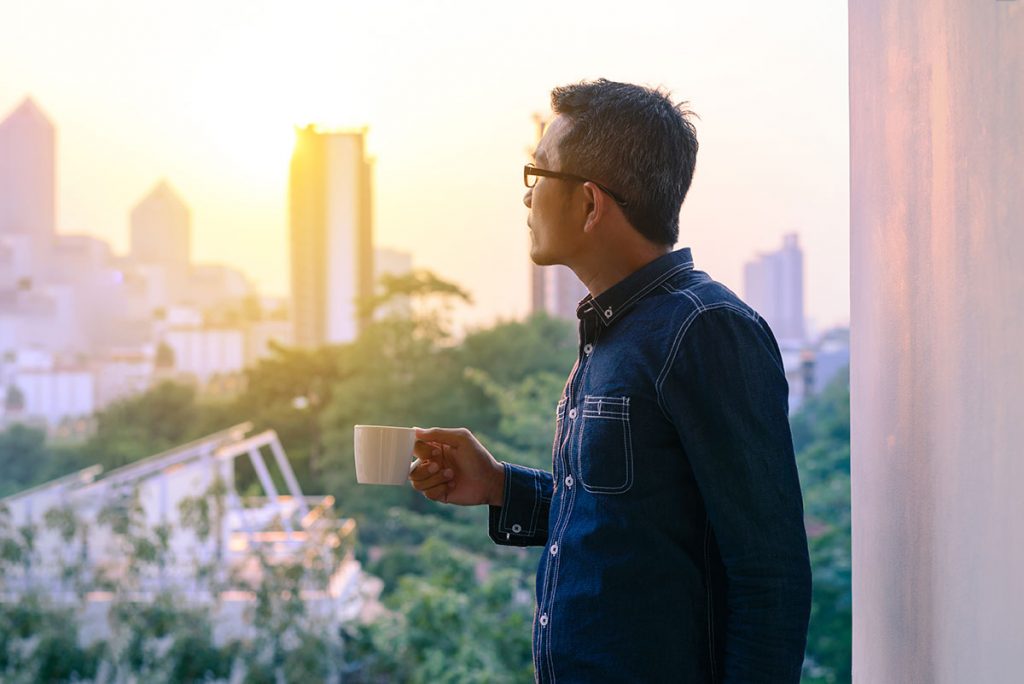 Business man looking out over Asian city with coffee