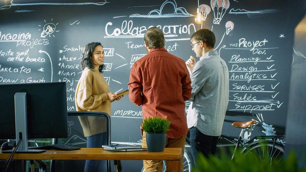 group of professionals talking by a blackboard