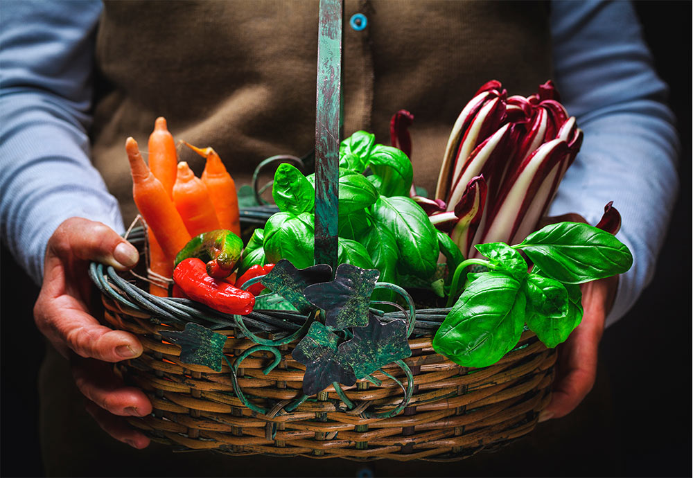 close up of man in the food and beverage industry holding basket of fresh vegetables
