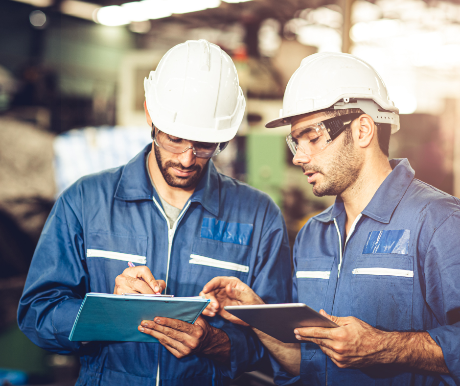 Regulatory compliance - two men in hard hats reviewing documents in a warehouse