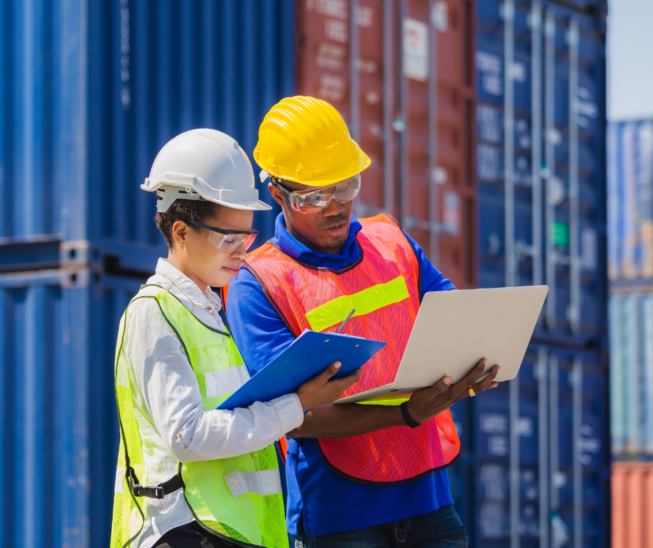 workers with clipboard and laptop next to shipping containers