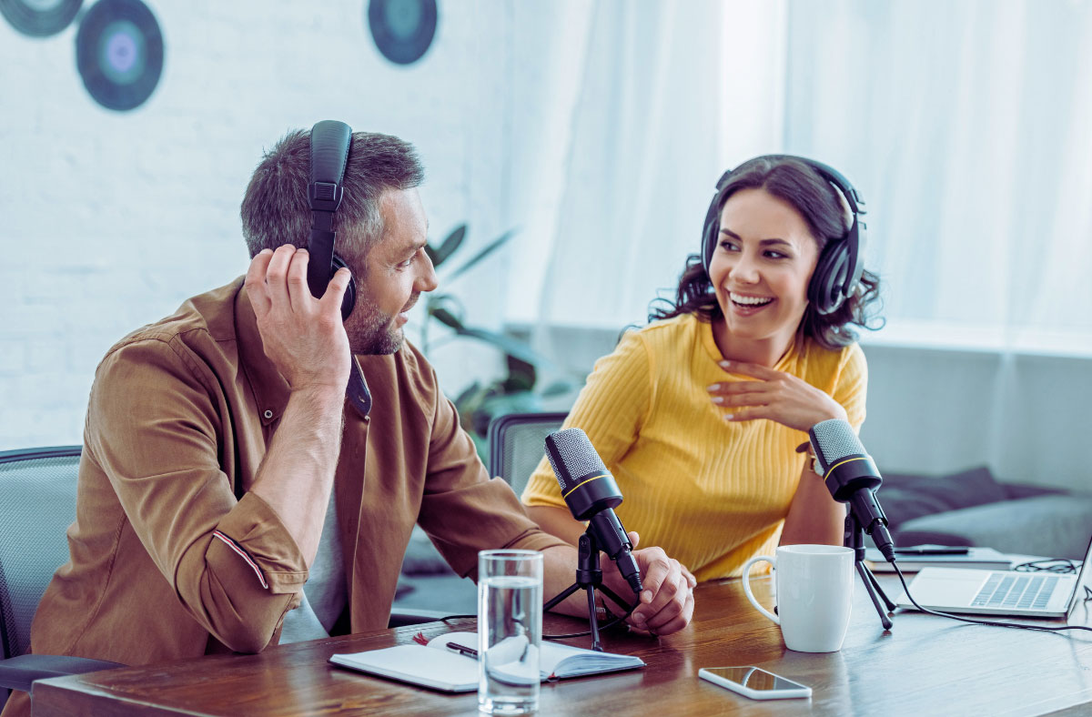 Two hosts recording a podcast wearing headphones with microphones in front of them